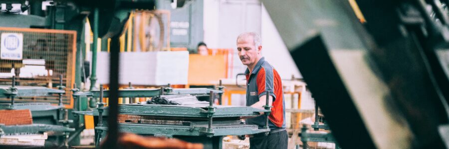 Employé d'une PME manufacturière québécoise devant une ligne de production automatisée